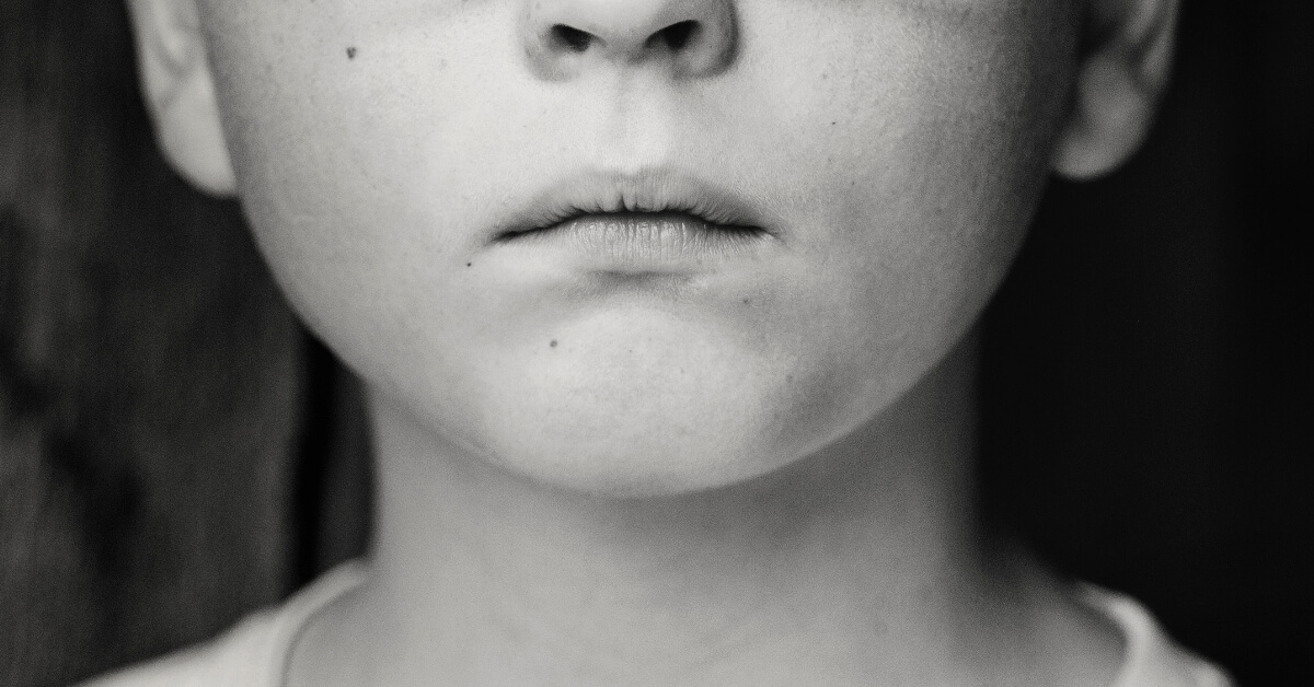 black and white bottom half of a boy's face with pursed lips