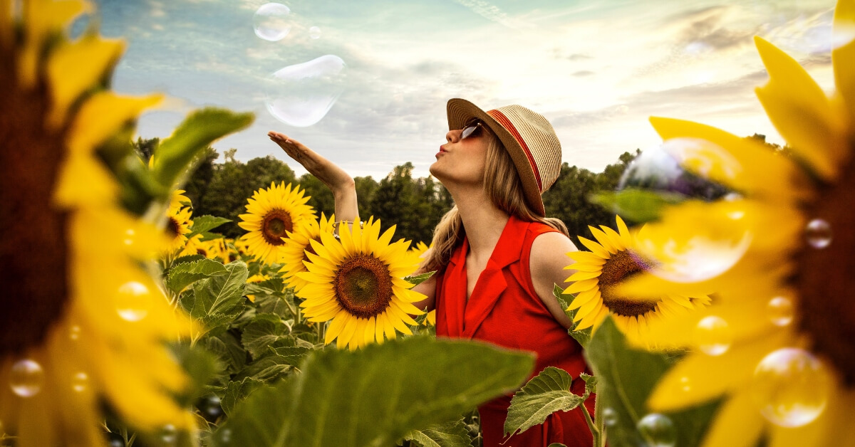 a woman blowing bubbles in a sunflower field