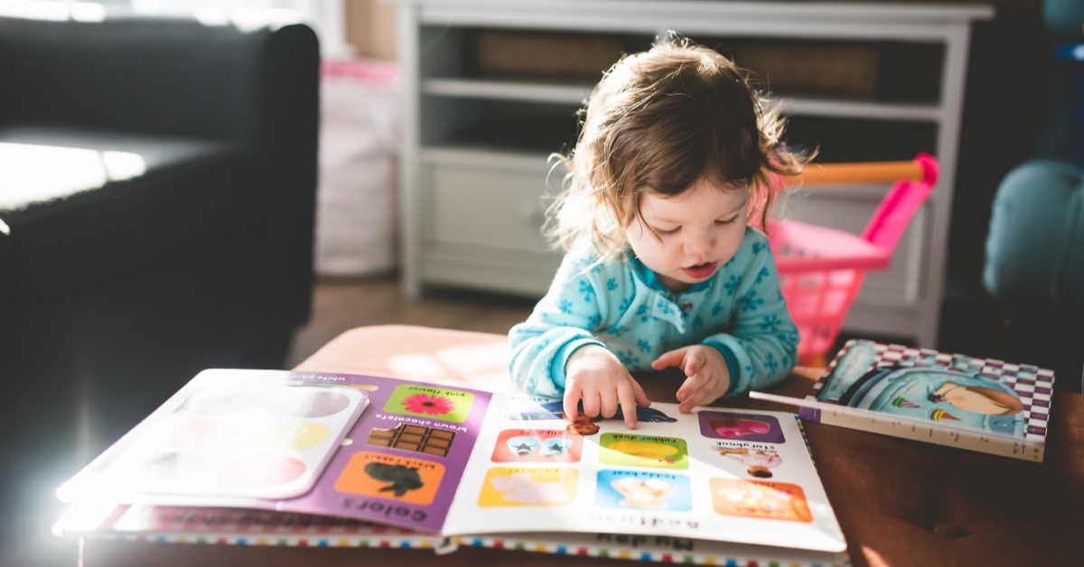 Little girl leaning over alphabet book