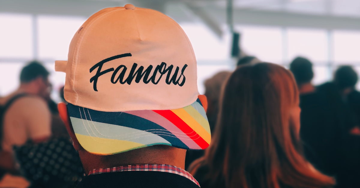 Guy in crowd with modern cap facing backwords reading 'famous'