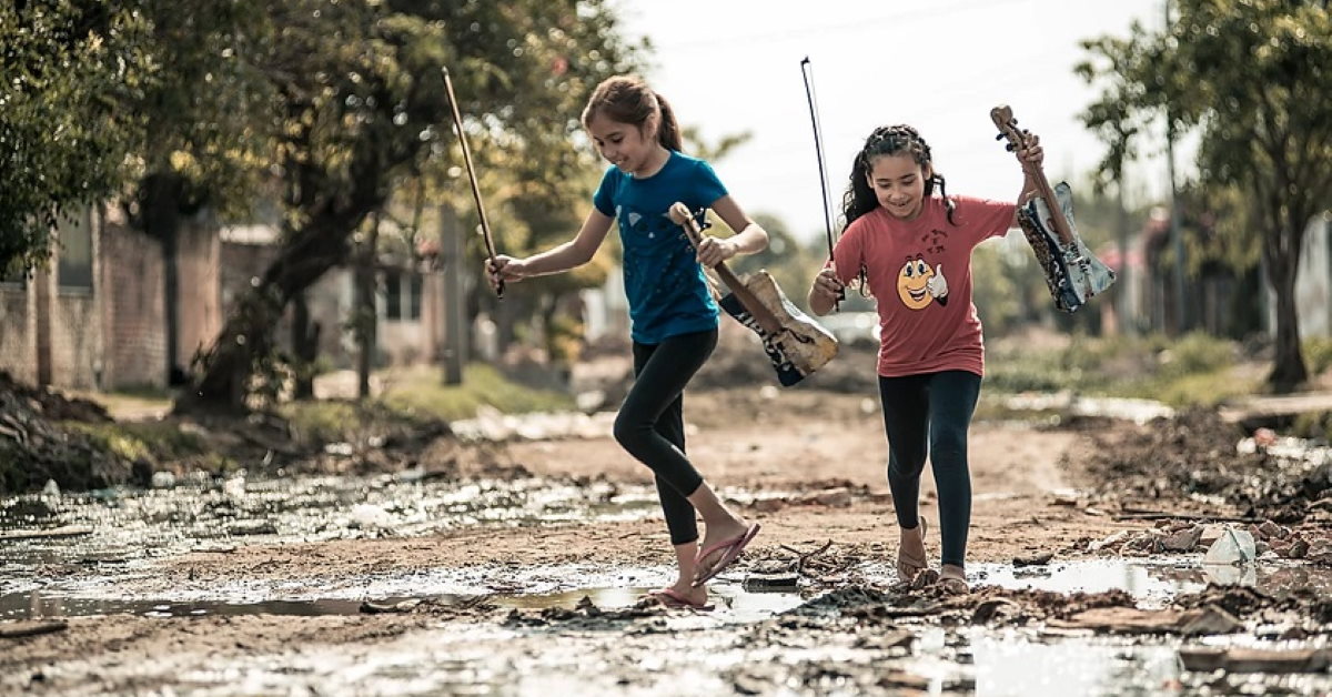 girls with violins playing in the mud