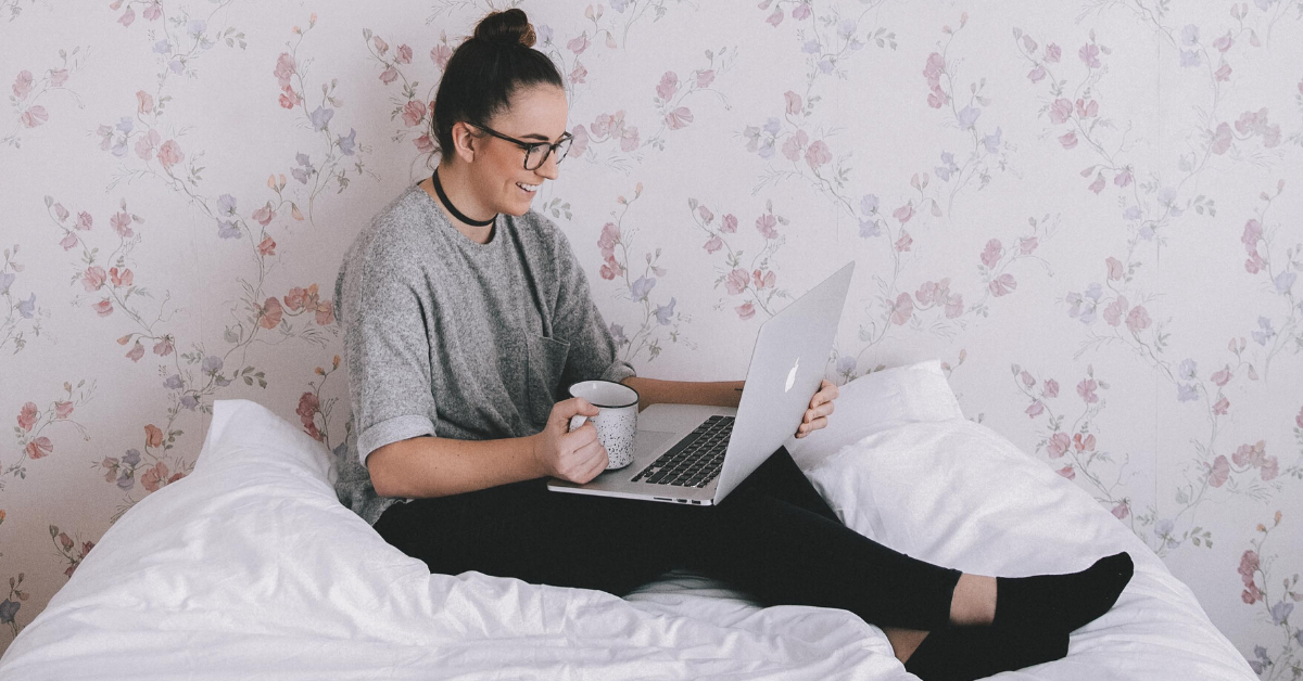 girl sitting in bed with laptop smiling