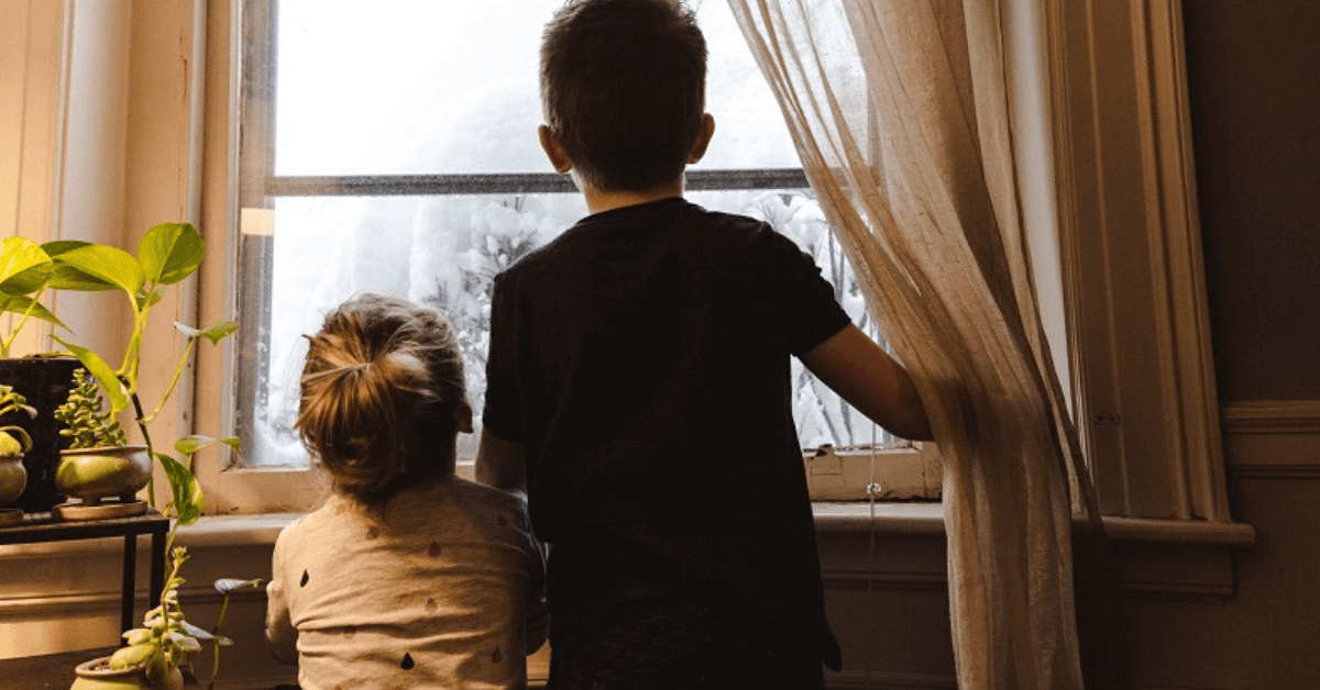 2 kids looking out a window