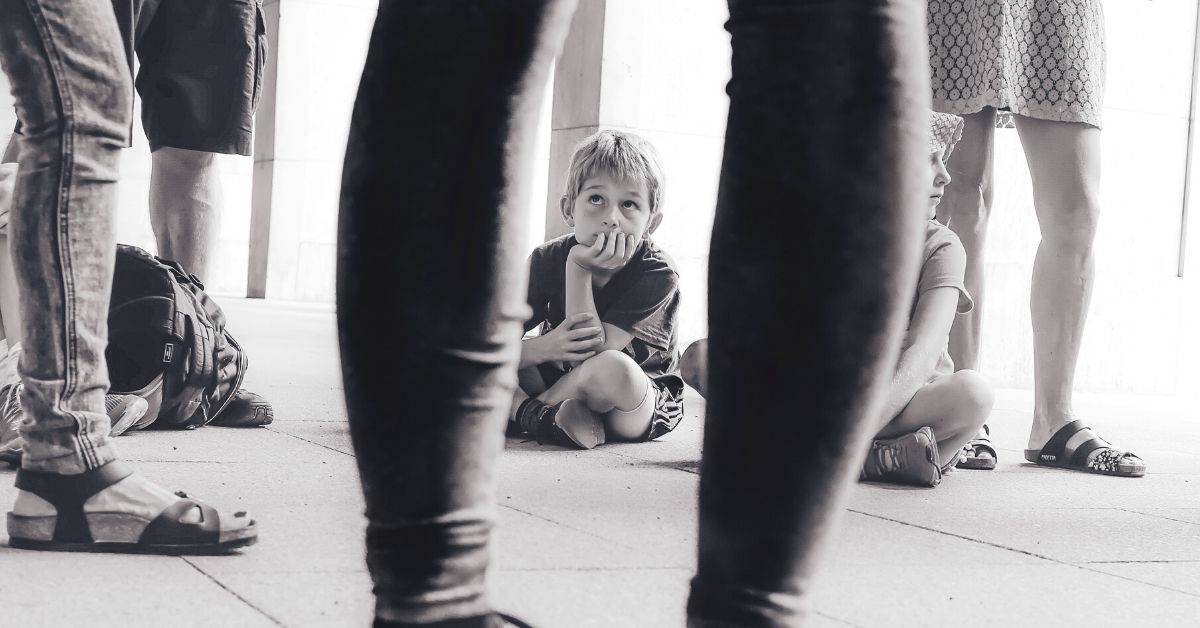 young boy sitting on floor looking up at someone