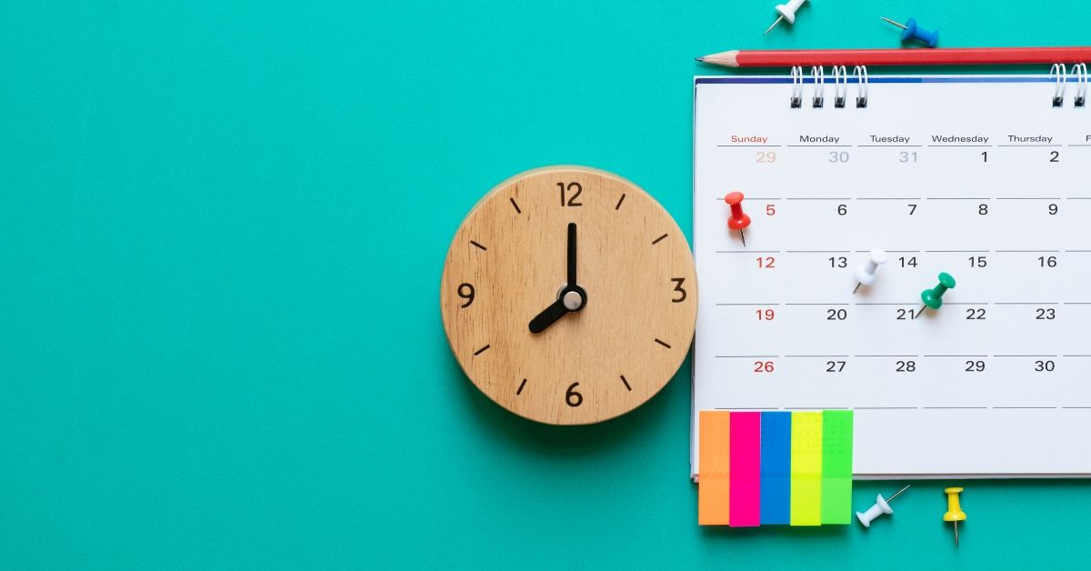 photo of a calendar, clock and sticky notes on a green background