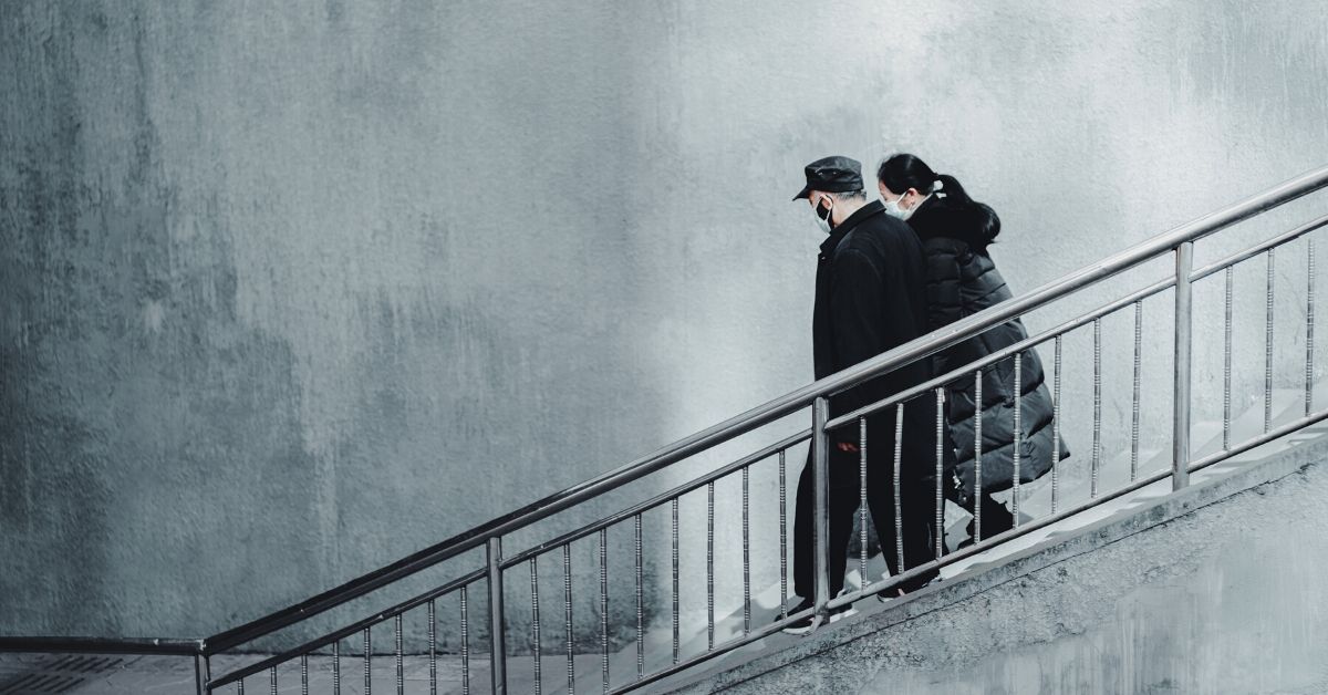 a photo of a man and a woman wearing masks due to the COVID-19 pandemic walking down stone stairs