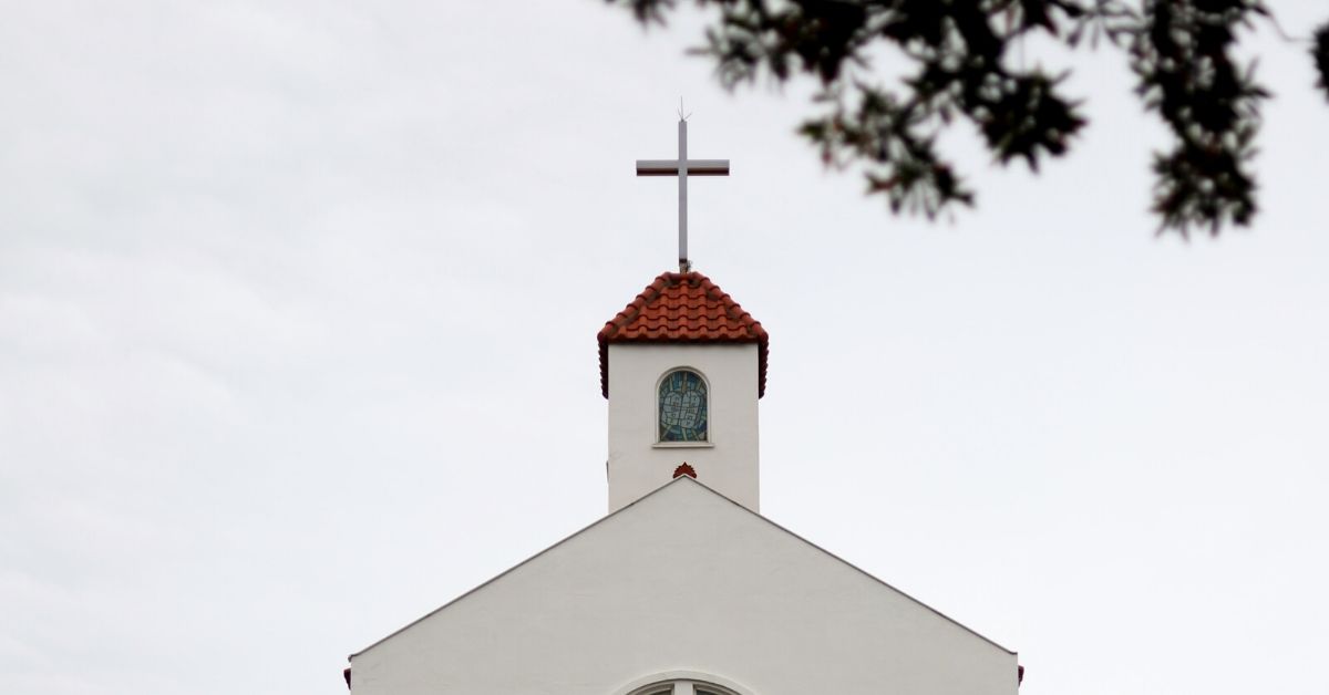 photo of church's roof which has a cross on top
