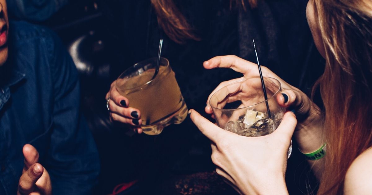 photo of two women talking holding drinks