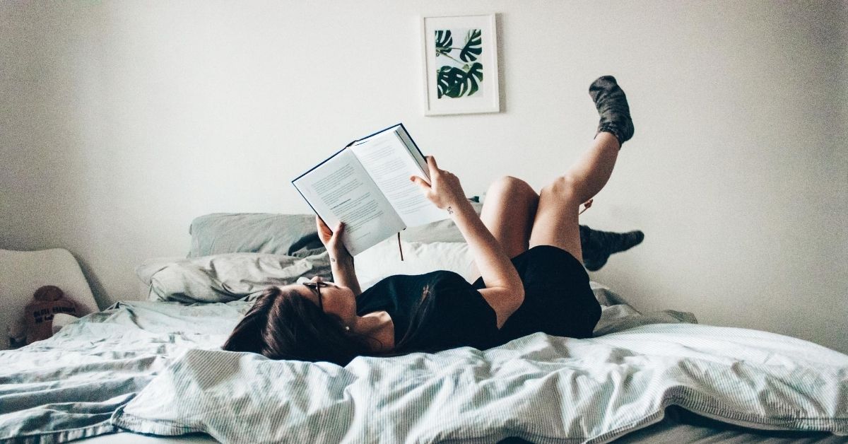 a woman laying on her bed reading a book
