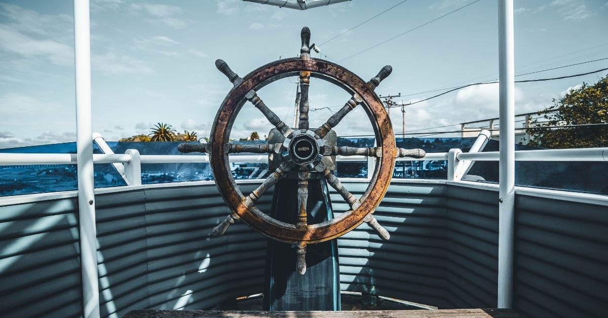 a wooden steering wheel on a boat overlooks blurry water