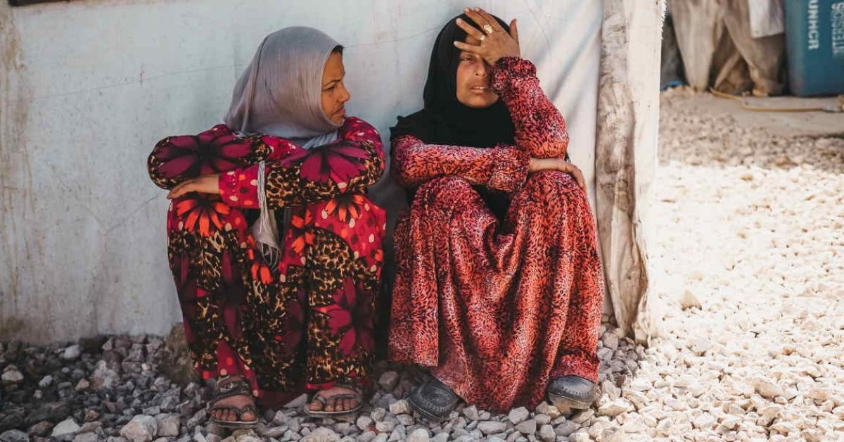 two middle eastern women sitting on ground