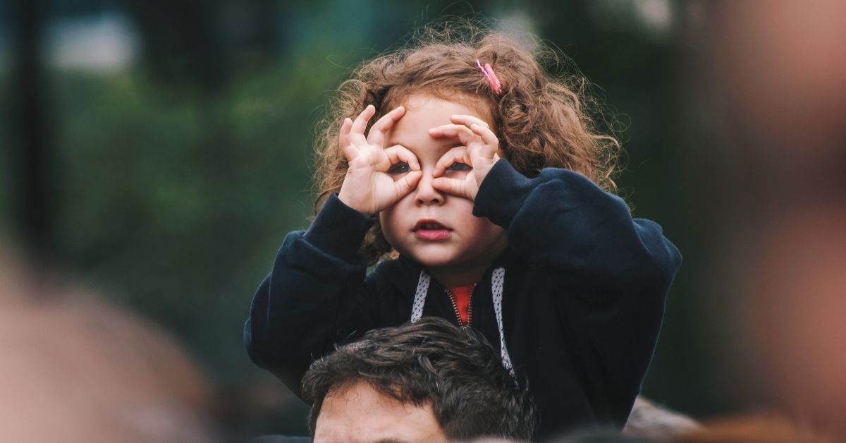 young girl forming glasses over her eyes with her hands