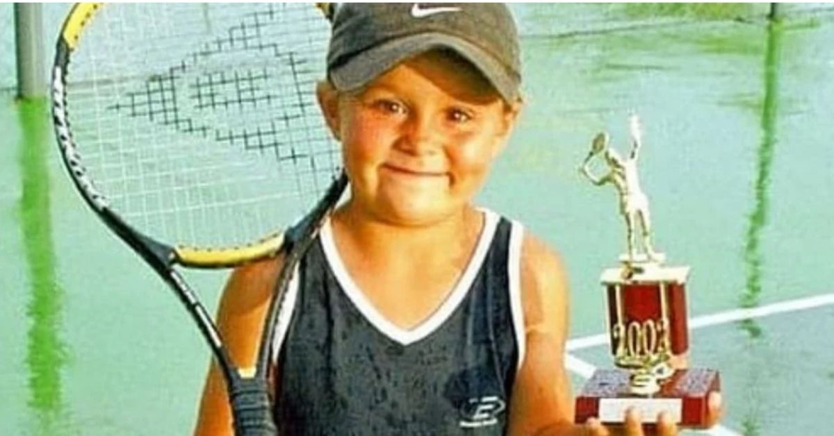 young ash barty holding a racquet and trophy