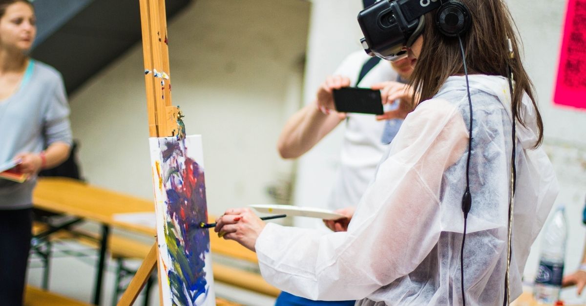students paints a canvas wearing a VR headset