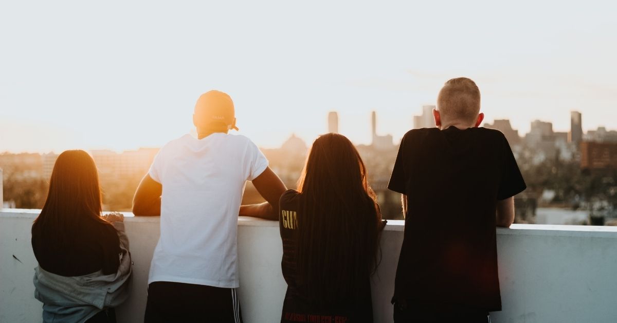 four young people gaze at a sunset over the city