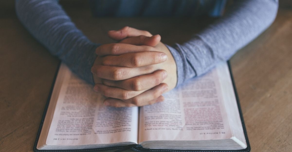 Person praying with Bible Open - Unsplash